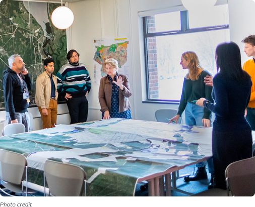 People are standing around a conference table looking at paperwork