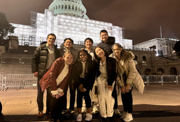 group of people posing in front of lit domed building at night