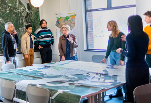 People are standing around a conference table looking at paperwork