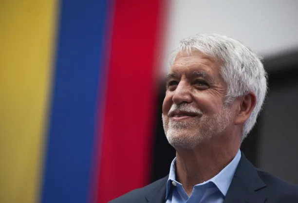 Enrique Peñalosa Londoño headshot against Colombian flag backdrop